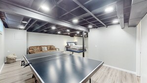 Ein Zimmer mit Tischtennisplatte, einer Couch und einem Bett.