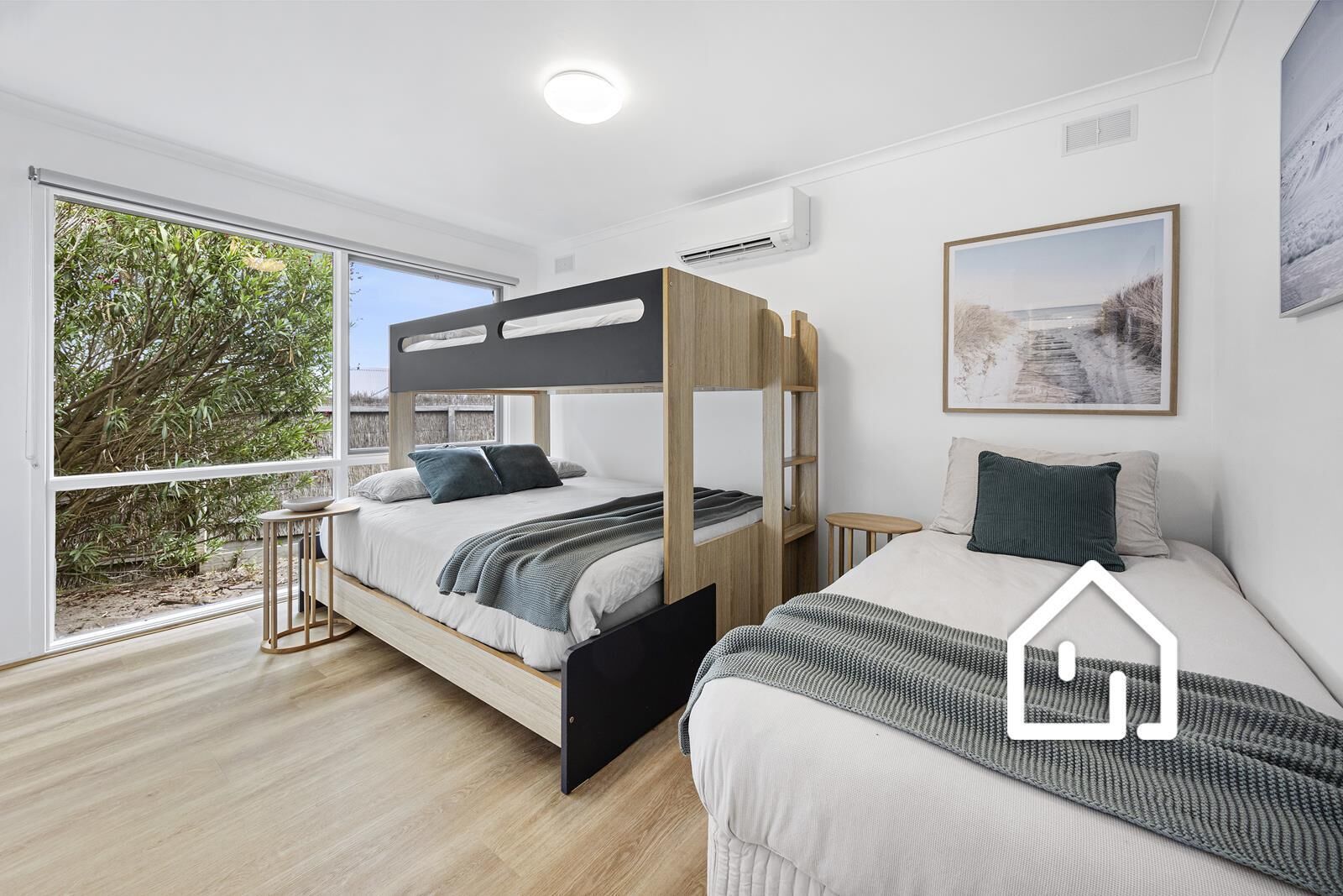 Un dormitorio moderno con una cama litera, una cama individual y un ventanal con vistas a zonas verdes.