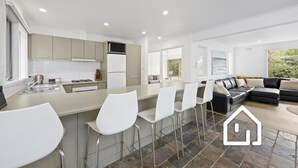 A modern kitchen with a central island, bar stools, and a dining area. - Albany Beachside Retreat *1 NIGHT FREE* (Sorrento)