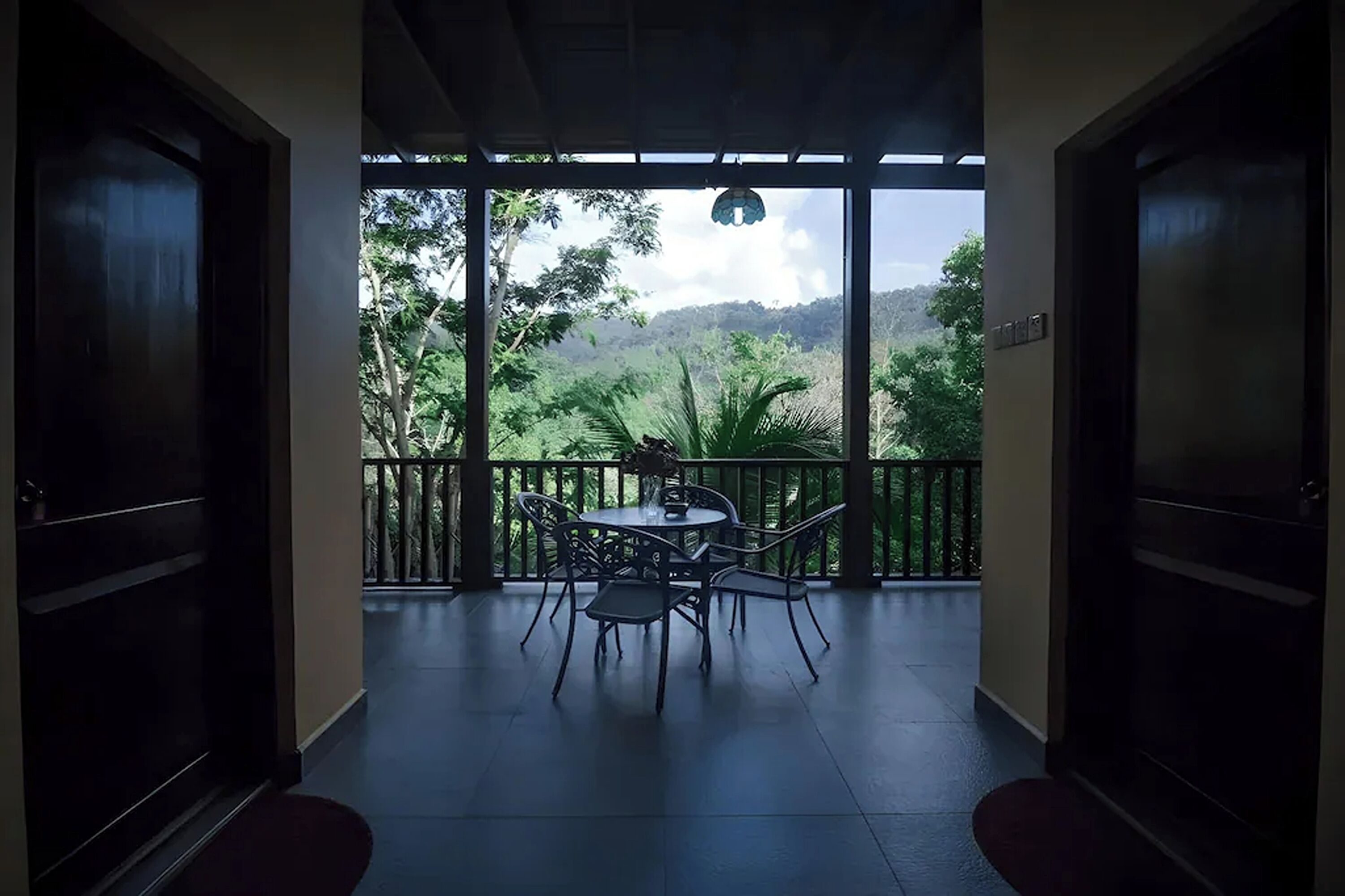 A room with a balcony, a table, and chairs.