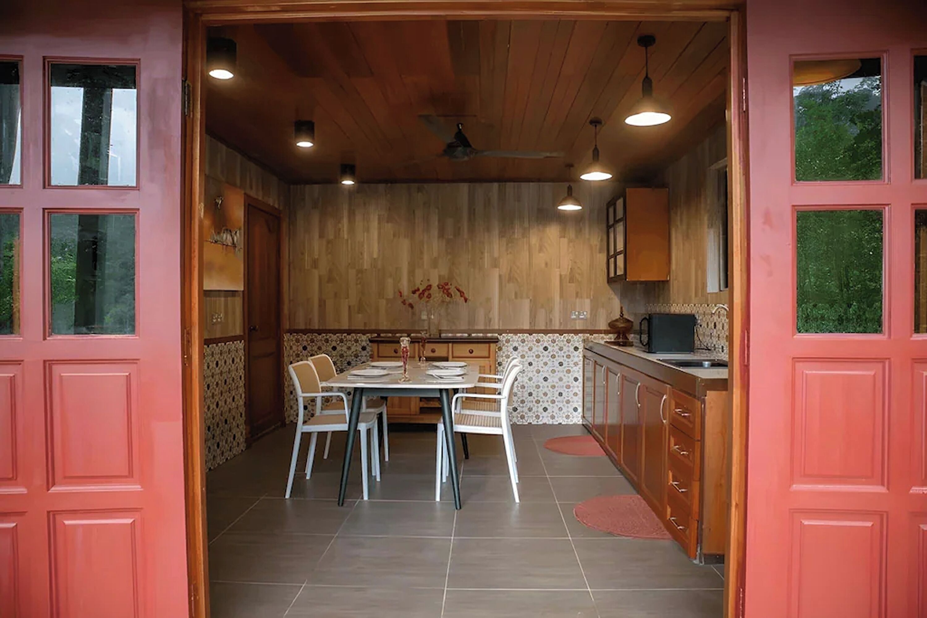 A dining area with a wooden ceiling, a dining table with chairs, and a kitchen area with cabinets and a sink.