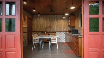 A dining area with a wooden ceiling, a dining table with chairs, and a kitchen area with cabinets and a sink.