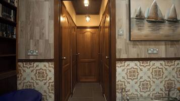 A hallway with patterned walls, a wooden door, and a painting of sailboats.