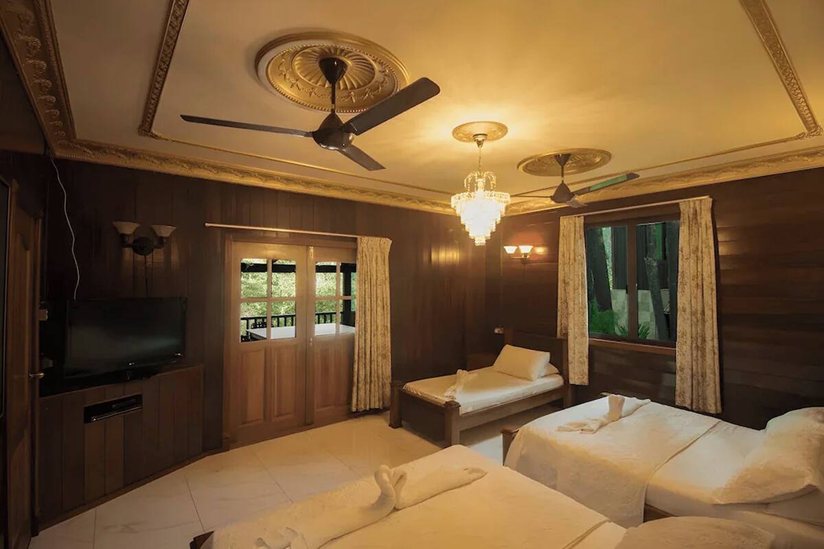 Ein Hotelzimmer mit zwei Betten, einem Fernseher, Deckenventilatoren und einer Kristallleuchtre.