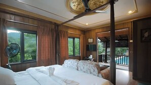 Ein Hotelzimmer mit einem großen Bett, einem Ventilator und Blick auf einen Balkon mit einem Pool.