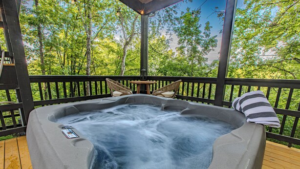 A hot tub on a wooden deck with a view of trees. - New - Dollywood - Fire pit - Arcade - Family Getaway (Sevierville)