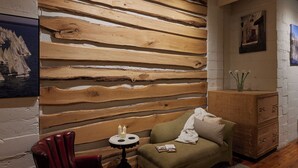 A cozy room with a wooden slat wall, a red leather chair, a small round table with candles, a green sofa, and a wooden cabinet. - Luxury Loft in the Rochester Public Market! (Rochester)