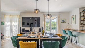 A modern dining area with a wooden table set for six, surrounded by vibrant chairs.