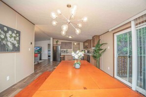 Una cocina amplia con una isla grande, un comedor con mesa de madera y una lámpara moderna.