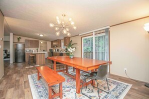 Una cocina amplia con armarios de madera, una isla central y un comedor con mesa y banco de madera.