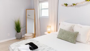 A neatly arranged bedroom with a bed, bedside table, and a mirror.