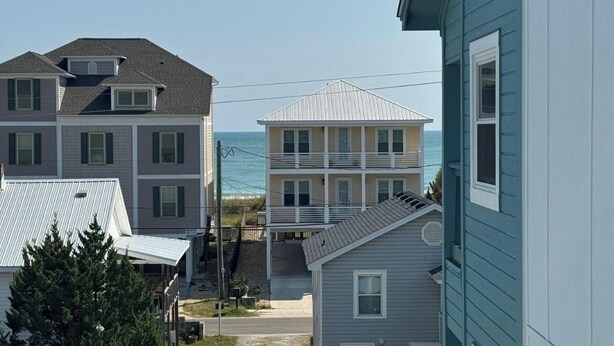 Un quartier résidentiel situé sur la côte, avec des immeubles à plusieurs étages, dont une maison à deux étages dotée d’un balcon et une maison plus petite avec un toit à pignon.