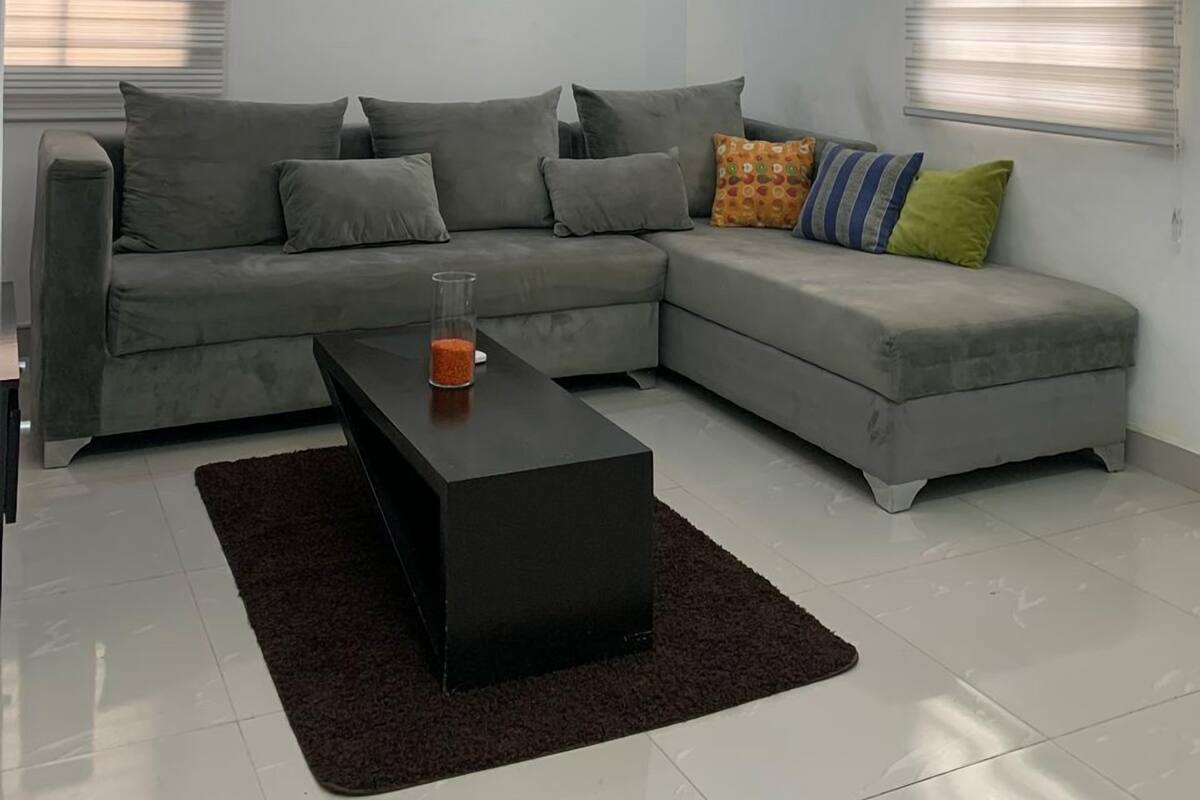 A modern living room with a sectional sofa, a black coffee table, and a glass vase with red pebbles.