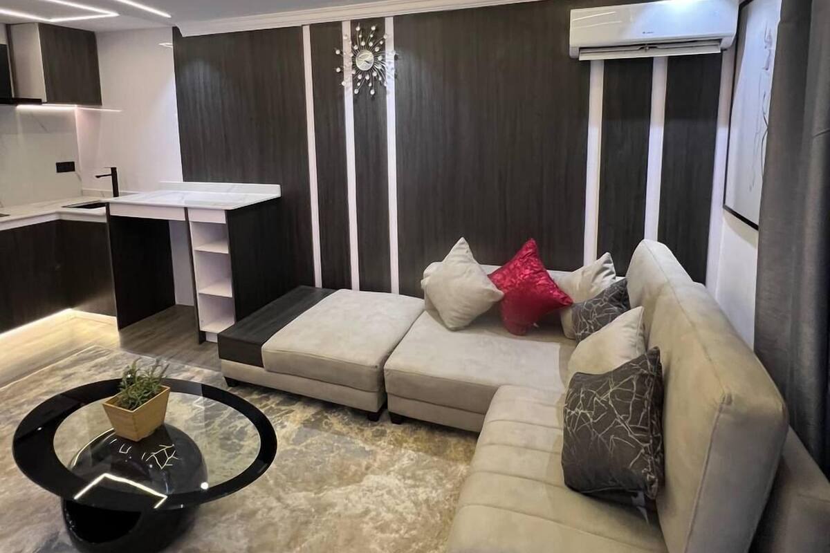 A modern living room with a sectional sofa, a coffee table, and a decorative clock.