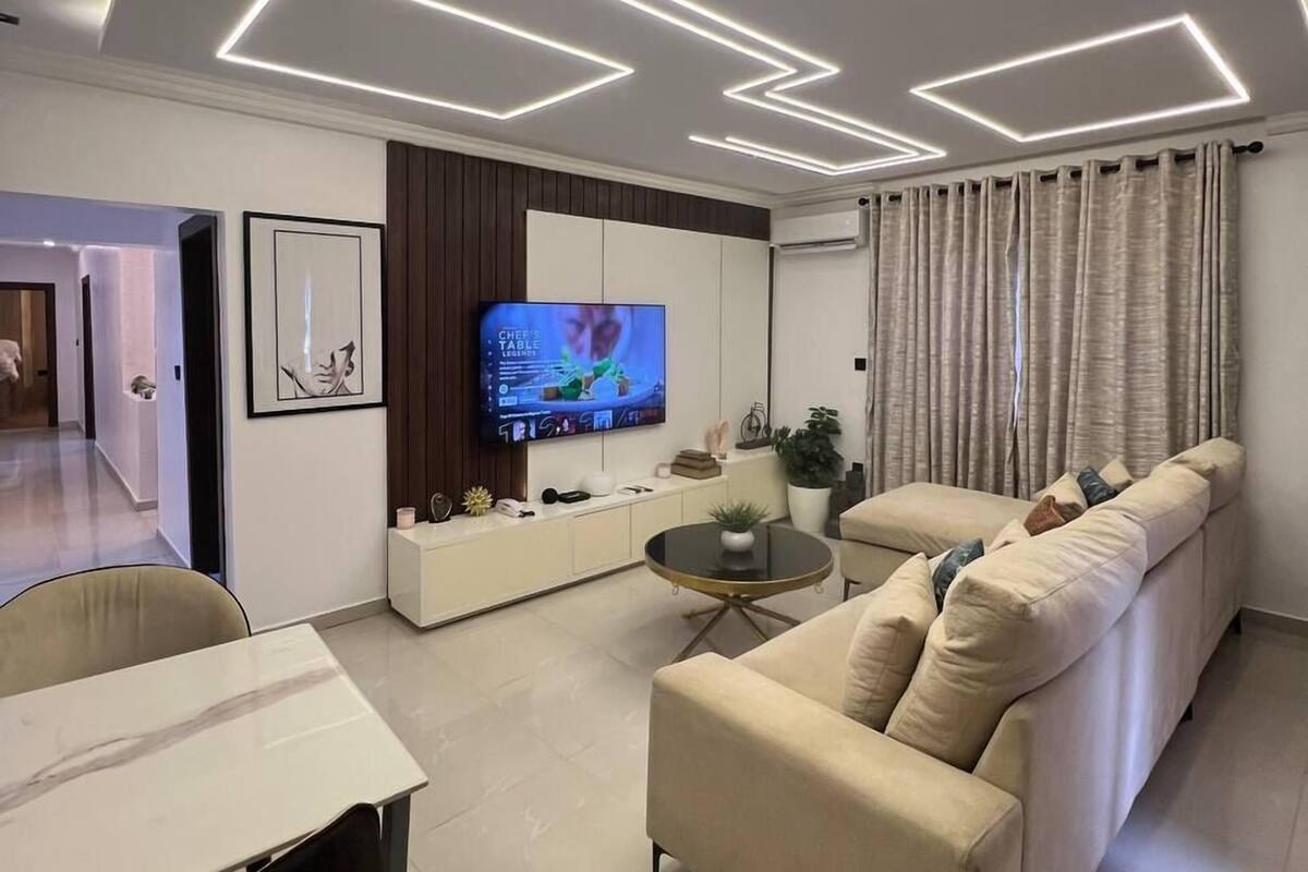 A modern living room with a sofa, a TV, and a dining area.