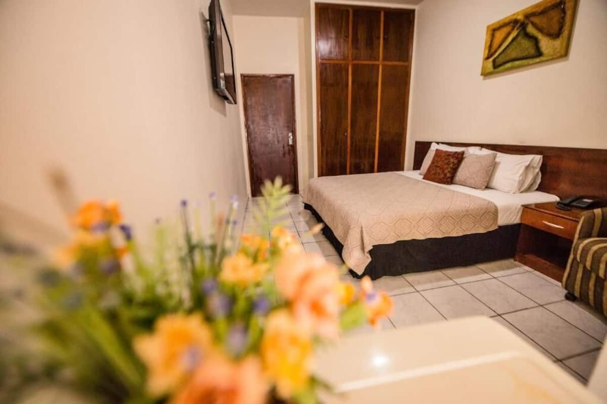 A bedroom with a bed, bedside table, and a wooden wardrobe.