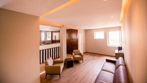 A spacious living area with a wooden floor, a brown sofa, and two armchairs. - Havana Economy (Uberaba)