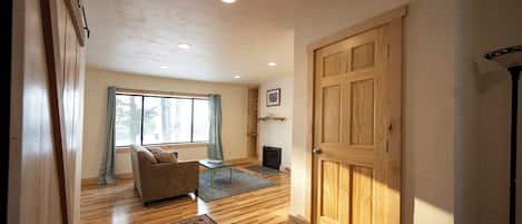 A spacious living room with a wooden floor, a sofa, a coffee table, and a fireplace.