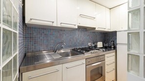 A modern kitchen with white cabinets, a stainless steel countertop, a gas stove, and a built-in oven. - Cozy apartment 5 minutes walk from the Colosseum (Roma)
