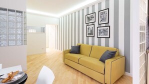 A living room with a yellow sofa, striped wallpaper, and framed pictures on the wall. - Cozy apartment 5 minutes walk from the Colosseum (Roma)