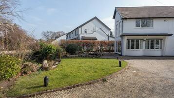 A two-story house with a gravel driveway and a well-maintained lawn.