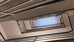 En modern inredning med ett tak som har ett geometriskt mönster, ett takfönster och ett vanligt fönster.