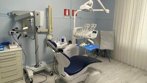 En tandläkarmottagning med en behandlingsstol, tandläkarutrustning och en ljuskälla.
