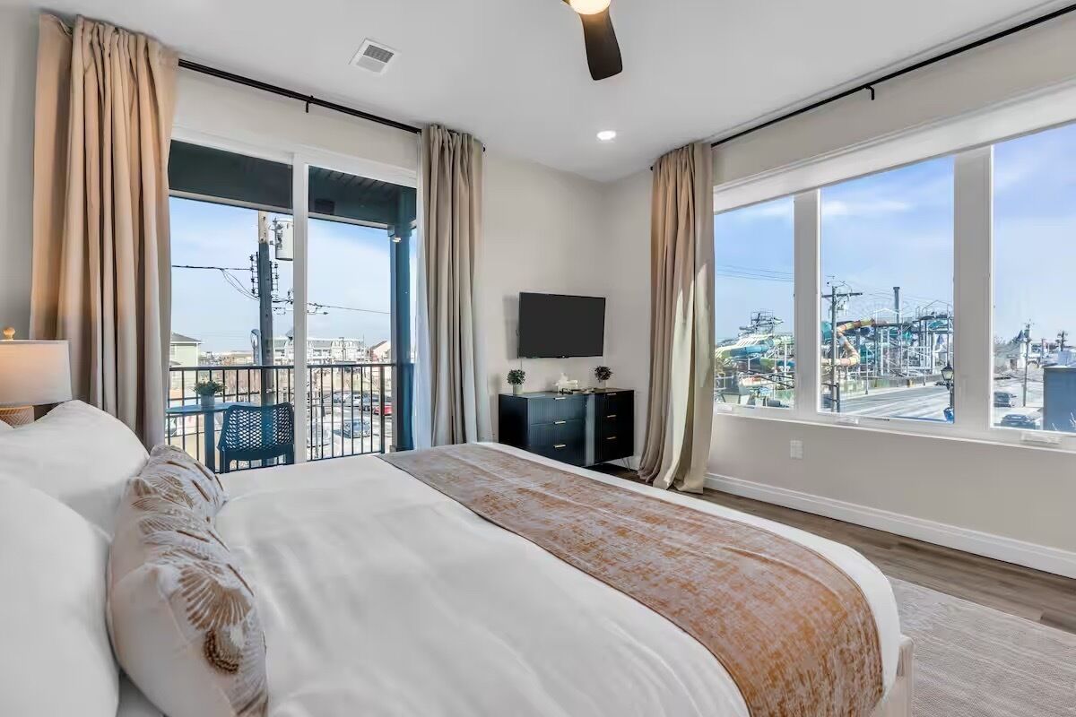Une chambre dotée d’un grand lit, d’une télévision, d’une commode et d’un balcon offrant une vue sur la ville.