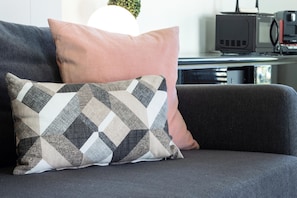 A sofa with patterned cushions and a microwave on a counter.