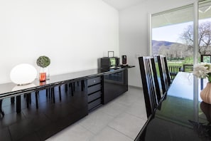 A modern kitchen with a black countertop, a small island, and a view of a park through a large window.