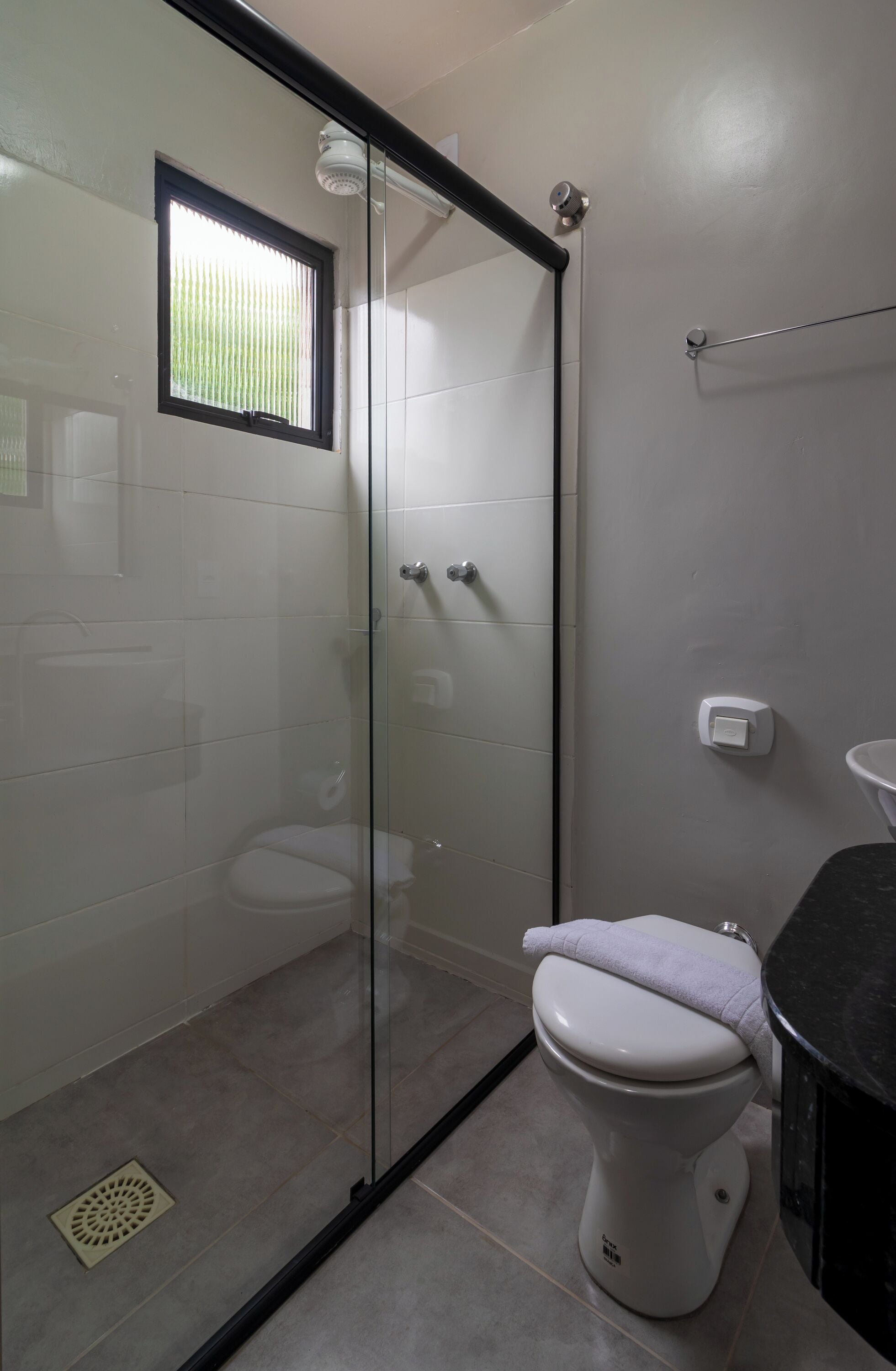 A bathroom with a glass-enclosed shower, a toilet, and a sink.