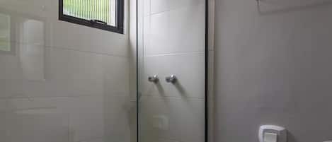 A bathroom with a glass-enclosed shower, a toilet, and a sink.