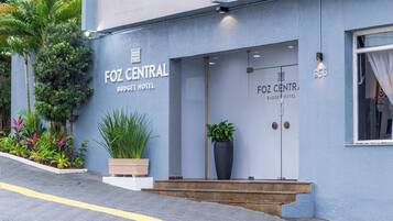 Exterior do Hotel Foz Central Budget, com fachada moderna, ampla entrada e plantas em vasos.