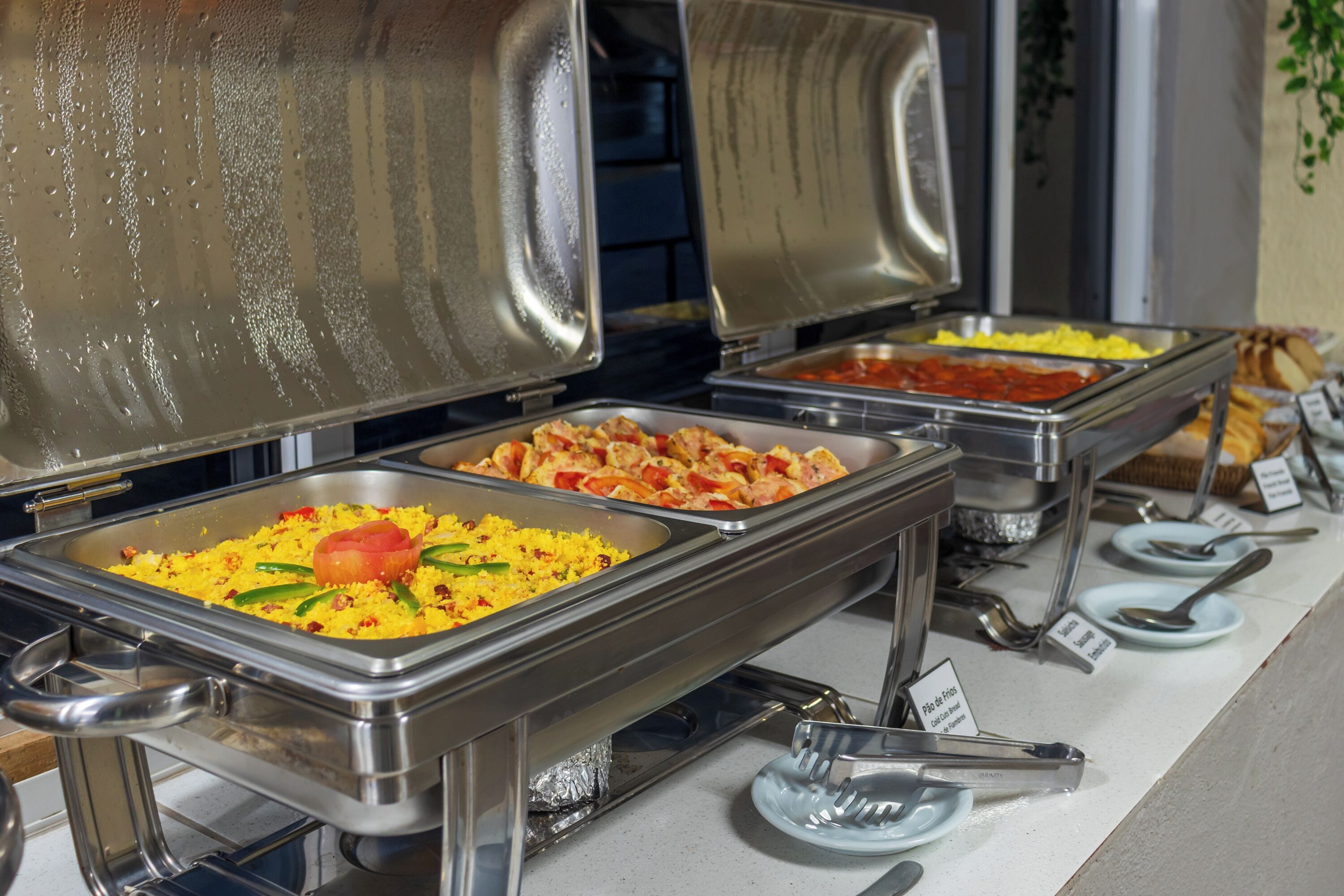 Un bufé con diversos platos, incluyendo arroz con verduras y un centro de tomate, y un cartel que indica una opción vegetariana.