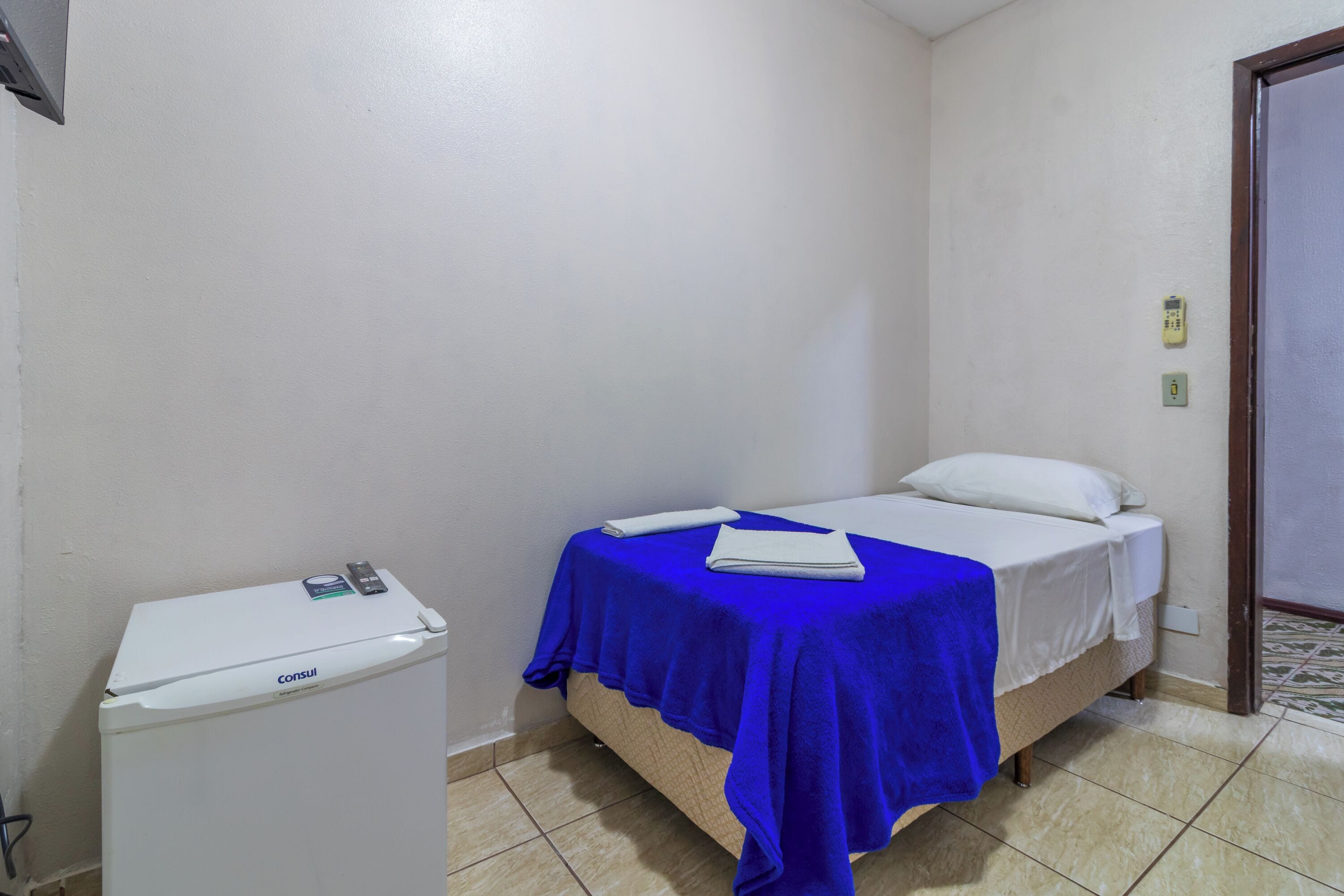 A small room with a bed, a white heater, and a door.