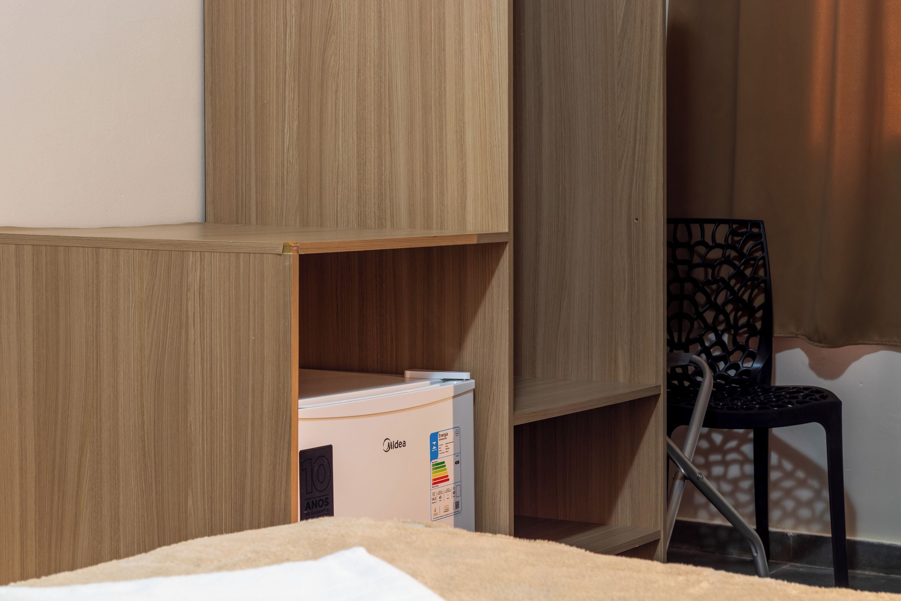 A room with a bed, a wooden wardrobe, and a chair.