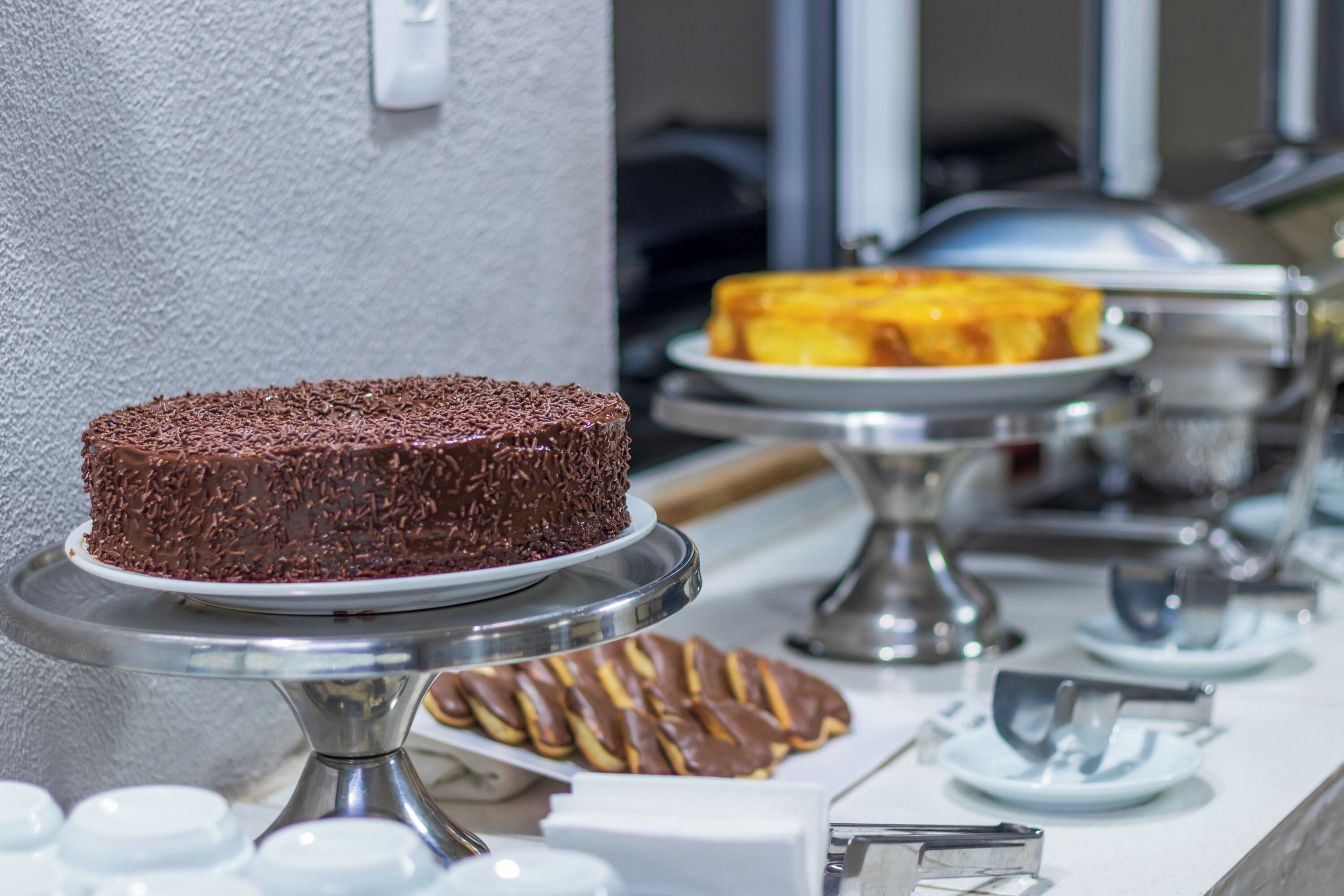 Un bufé con diversos postres a la vista, incluyendo un pastel de chocolate y un pastel de queso.