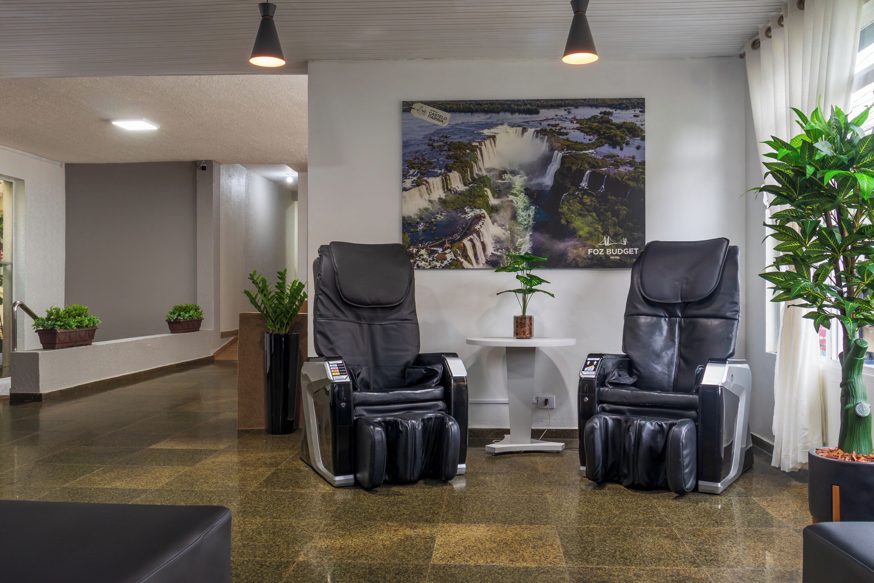 A spa area with two massage chairs, a wall-mounted poster, and potted plants.