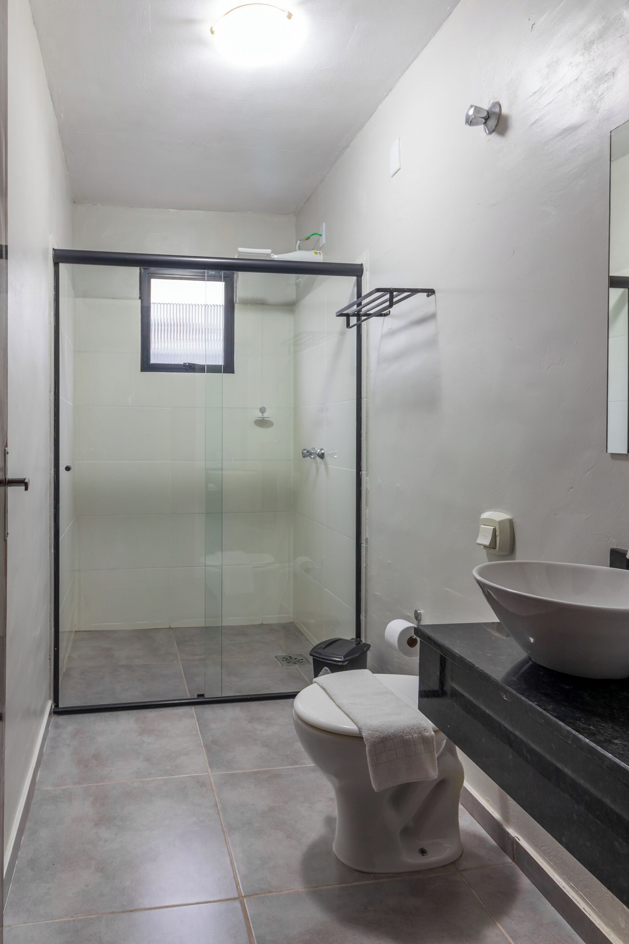 A modern bathroom with a glass-enclosed shower, a white toilet, and a large vessel sink.