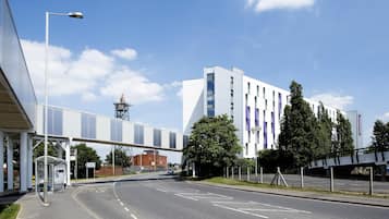 A modern building with a covered walkway, a bus stop, and a clear sky.