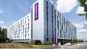 Un hôtel moderne, reconnaissable à son enseigne « Premier Inn » bien visible, à sa façade sobre et à son parking situé à l’avant.