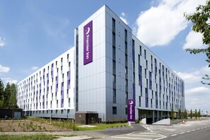 Egy modern szállodai épület, amelyen feltűnő „Premier Inn” felirat látható, sík homlokzattal és egy parkolóval az elején.