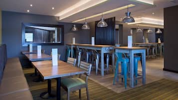 A modern restaurant with high tables, bar stools, and pendant lighting.