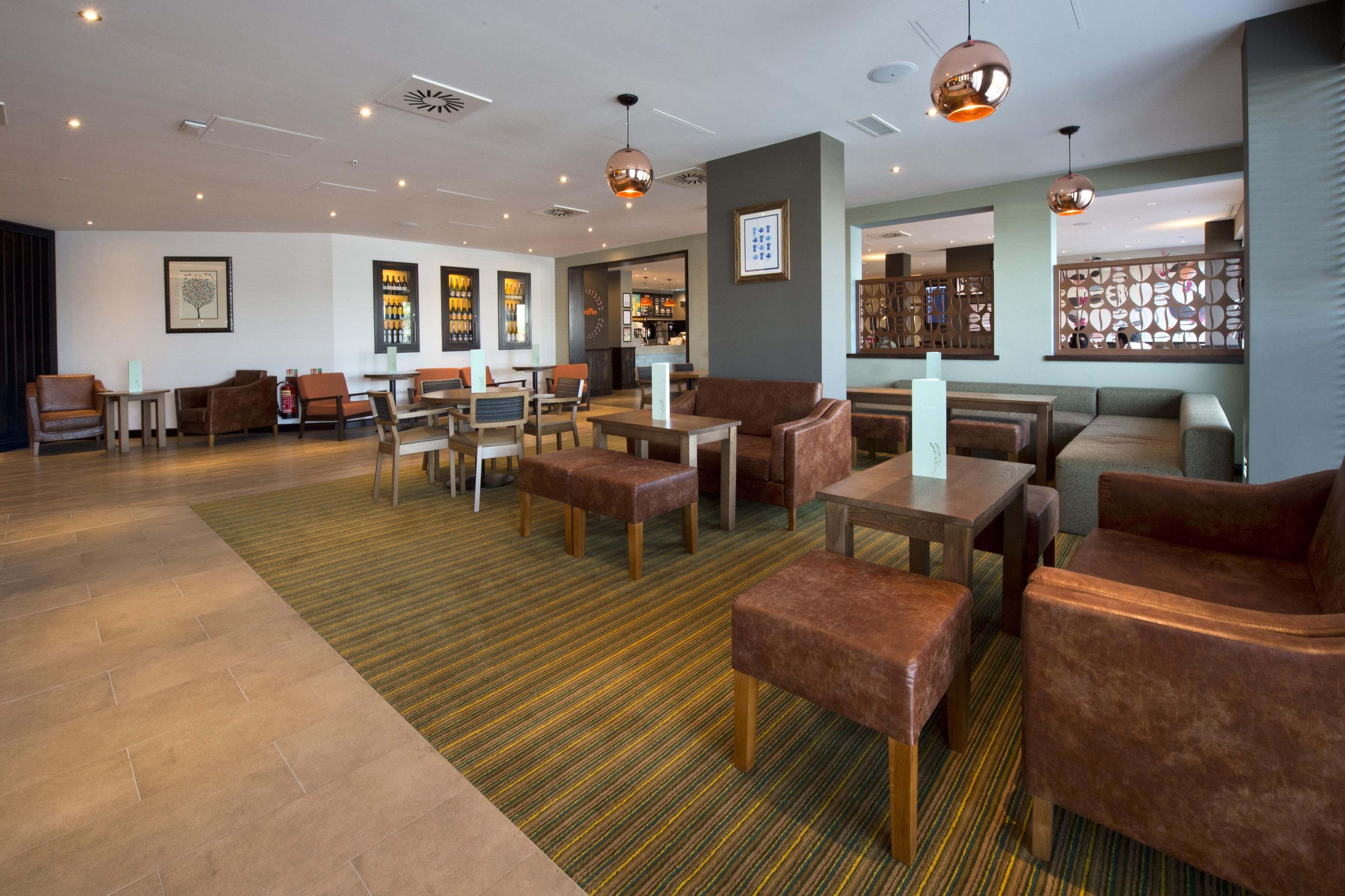 A modern lobby with seating areas, a reception desk, and a bar.