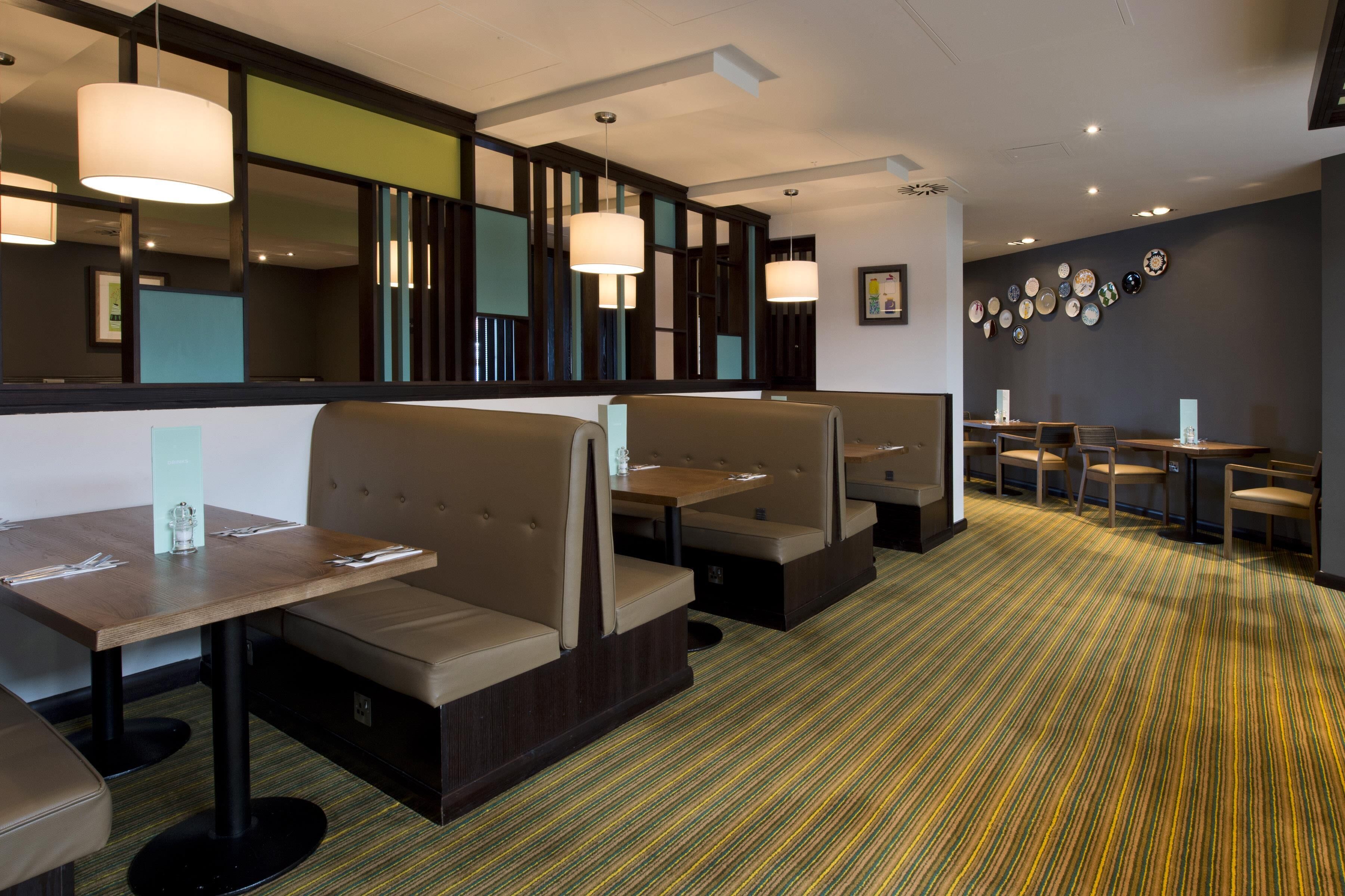 A restaurant with booths, tables, and a patterned carpet.