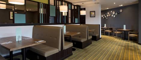 Un restaurante con cabinas, mesas y una alfombra estampada.