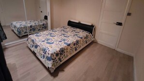 A bedroom with two beds, a large mirror, and a door. - South London 3 Bedroom House (Carshalton)