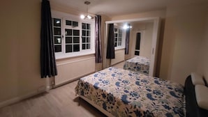 A bedroom with a bed, a window, a radiator, and a mirror. - South London 3 Bedroom House (Carshalton)