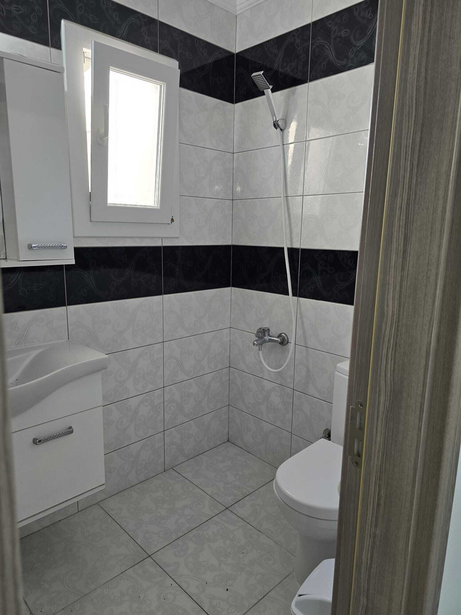 A bathroom with a toilet, a sink, a shower, and a window.