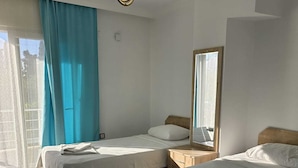 A hotel room with two beds, a large window with curtains, a hanging light fixture, and a mirror on the wall. - Elfida Apart Palamutbükü (Datça)